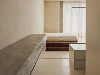 A minimalist bedroom with a concrete floor cabinet and a bed with a simple frame.