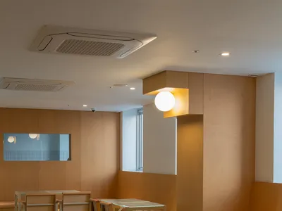 Modern restaurant interior featuring wooden seats and tables with a minimalist design.