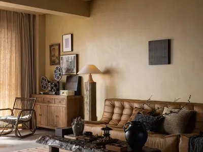 A living room with a brown leather sofa, dramatic lighting, and wooden accents.