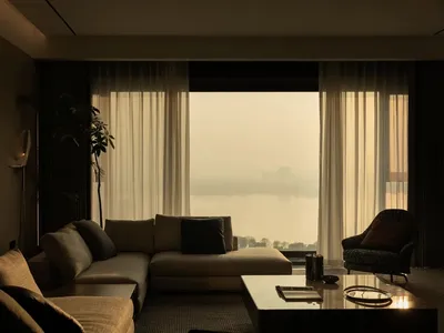 A luxurious living room with a large, transparent window overlooking a picturesque landscape, featuring a modern sofa and an