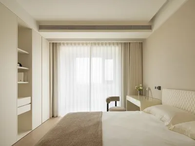 A minimalist bedroom with neutral-colored walls, furniture, and textiles, featuring clean lines and a serene atmosphere.