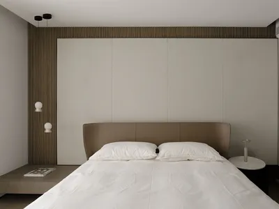 Modern minimalist bedroom with grey and taupe color scheme, featuring a simple bed and soft textiles.