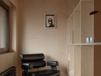 A minimalist home office with a black chair and wooden shelves.