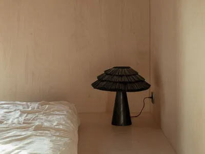 Minimalist bedroom with a black lamp and wooden walls.
