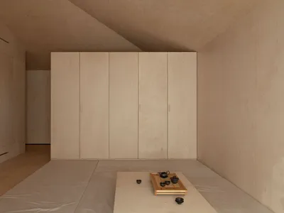 A minimalist bedroom with a white bed and wooden walls and floor.