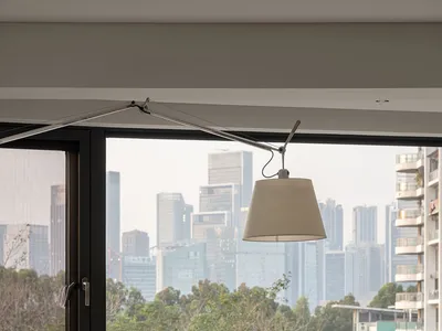 A modern home office desk situated in front of a large window overlooking a cityscape.