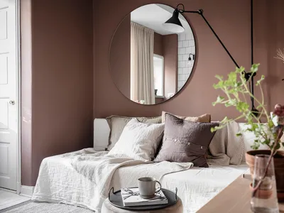A cozy living room with textured fabric furnishings and a round mirror