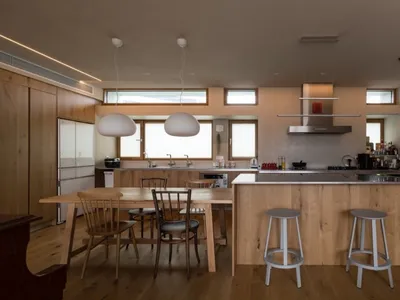 Modern kitchen featuring a wooden island and stools, with a pendant light hanging above the dining table and a stainless stee