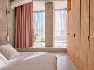A modern bedroom featuring concrete and wooden elements.