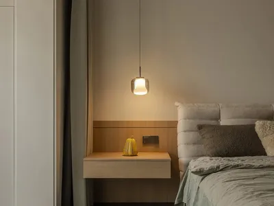 Minimalist bedroom with a wooden floating nightstand and a yellow lantern.