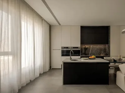 Modern minimalist kitchen with concrete elements and a black island counter.