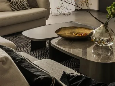 Modern living room with marble tables, a cozy sofa, and a sleek black fireplace.