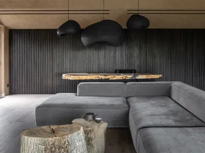 Industrial-style living room featuring wooden slat walls, a sectional sofa, and a rustic wooden coffee table with a tea set.