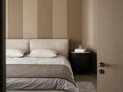 A minimalist bedroom with a bed, pillows, and a nightstand with a glass and books.