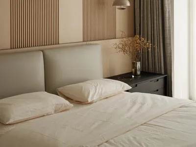 A minimalist bedroom featuring a wooden wall, potted plants, and a hanging pendant light.