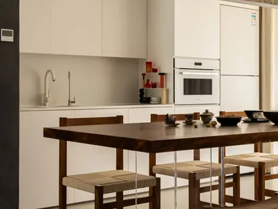 Minimalist residential kitchen featuring wood furniture and white appliances.