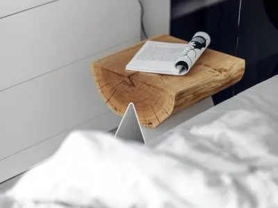 Minimalist bedroom featuring a wooden stool and metallic bedside lamp.