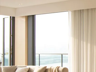 Modern, cozy living room with beige fabric furniture and large windows overlooking the outdoors.
