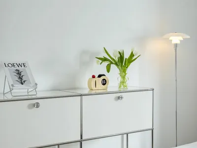 A minimalist bedroom featuring a glass cabinet, white tulips, and a floor lamp.
