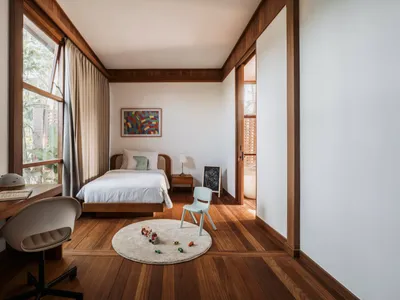 A child's bedroom featuring modern minimalist design with wood flooring, toys on a rug, and a single bed.