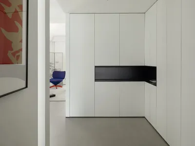A minimalist kitchen with white cabinetry and a black countertop.