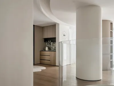 A modern, minimalist kitchen with white marble countertops and wooden cabinets.