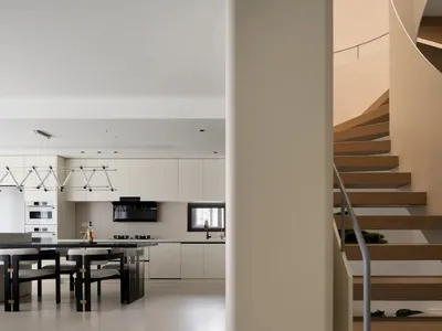 Minimalist modern kitchen and staircase intersection featuring wood stairs with concrete walls and floor.