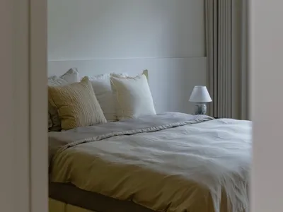 A modern bedroom with fabric bedding and minimalist decor.