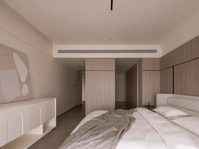 A modern minimalist bedroom with wooden paneling, a bed with a soft, light-colored headboard, and a contemporary art piece mo