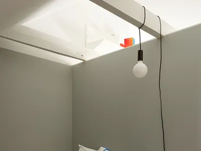 一間現代臥室，床上擺放著藍白格紋枕頭和橙藍圖紋毯子。
