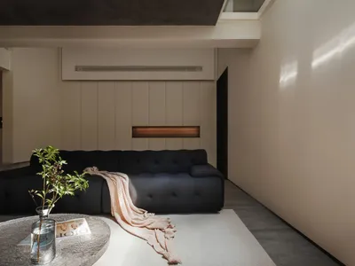 Minimalist living room featuring a concrete sofa and wooden paneling.