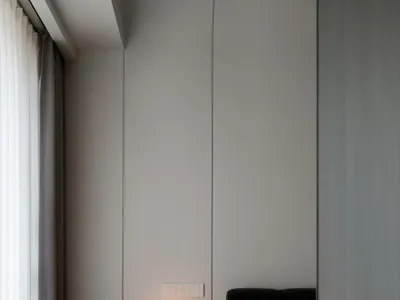 現代簡約臥室內擺放水磨石邊桌，桌上有一盞蘑菇造型燈，黑色的絎縫床架搭配粉色毯子