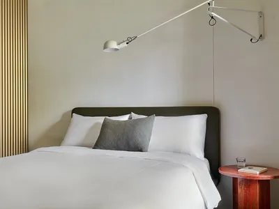 A minimalist bedroom featuring a white bed with a single decorative pillow.