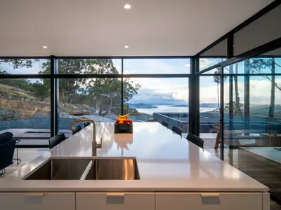 A modern kitchen featuring a large marble countertop with a stainless steel sink and a fruit bowl.