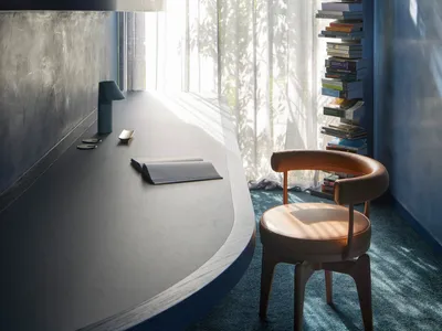 A well-lit, minimalist home office with a large window, modern wood desk, and comfortable chair.