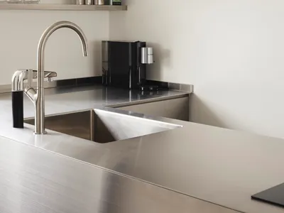 Minimalist modern kitchen with metallic stainless-steel surfaces, sleek design, and contemporary fixtures.