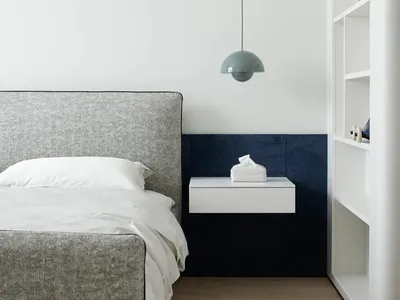 A bedroom with a modern design featuring a fabric bed, wooden flooring, and metal accents.