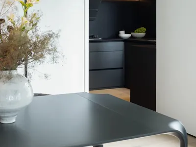 A modern minimalist kitchen with metallic surfaces, white cabinets, and a sleek design.