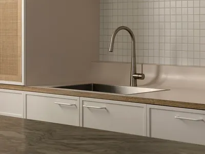 Minimalist, metal kitchen sink with stainless steel faucet and stone countertop.