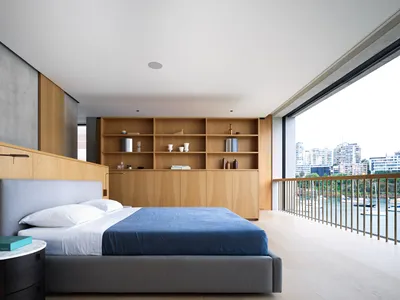 一間現代臥室，設有大床、木質層架，並可眺望城市景觀。