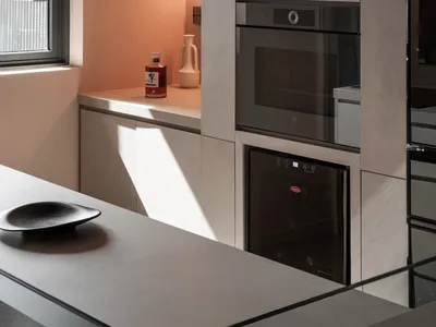 Modern minimalist kitchen with concrete cabinets, wall-mounted lamps, and a window.