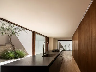 Modern kitchen with black countertops and wooden cabinets, featuring a sink and stove.