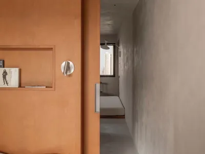 Minimalist bedroom featuring an orange wood headboard with a white bedspread