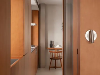 A modern kitchen with wooden cabinets, concrete floor, and a small dining area.