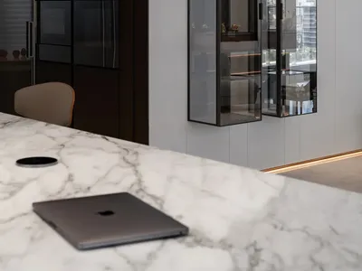 A modern kitchen featuring glass cabinets and a marble countertop.