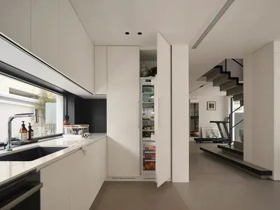 A modern, minimalist kitchen with white cabinets, a concrete countertop, and a black stove top oven.