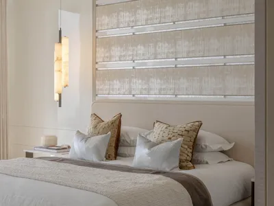A modern bedroom with a fabric-textured headboard and a pendant light hanging above the bed.