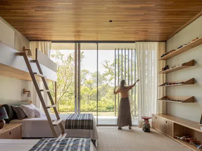 A modern bedroom with wooden furniture and a large window overlooking a green landscape.