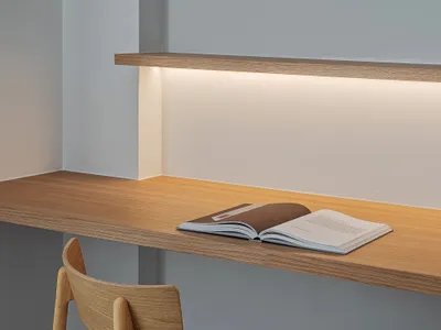 An open book on a modern, floating desk with ambient lighting in a minimalist home office setting.
