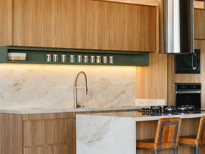 A modern kitchen interior featuring wooden cabinets and marble countertops.